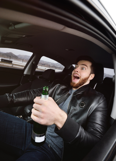 Hombre borracho con una botella de cerveza conduciendo un coche